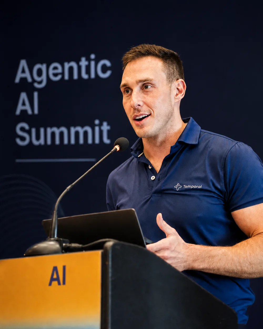Nikolay Advolodkin speaking at a podium in front of an Agentic AI Summit backdrop
